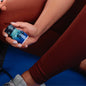 Person holding a smartphone with a blue screen, sitting on a blue surface.