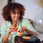 Woman holding two small bottles over a record player with a vinyl record on it.