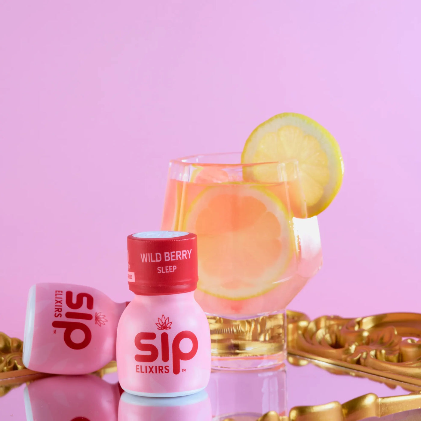Sip Elixirs Wild Berry Sleep bottle with a glass of pink drink on a pink background
