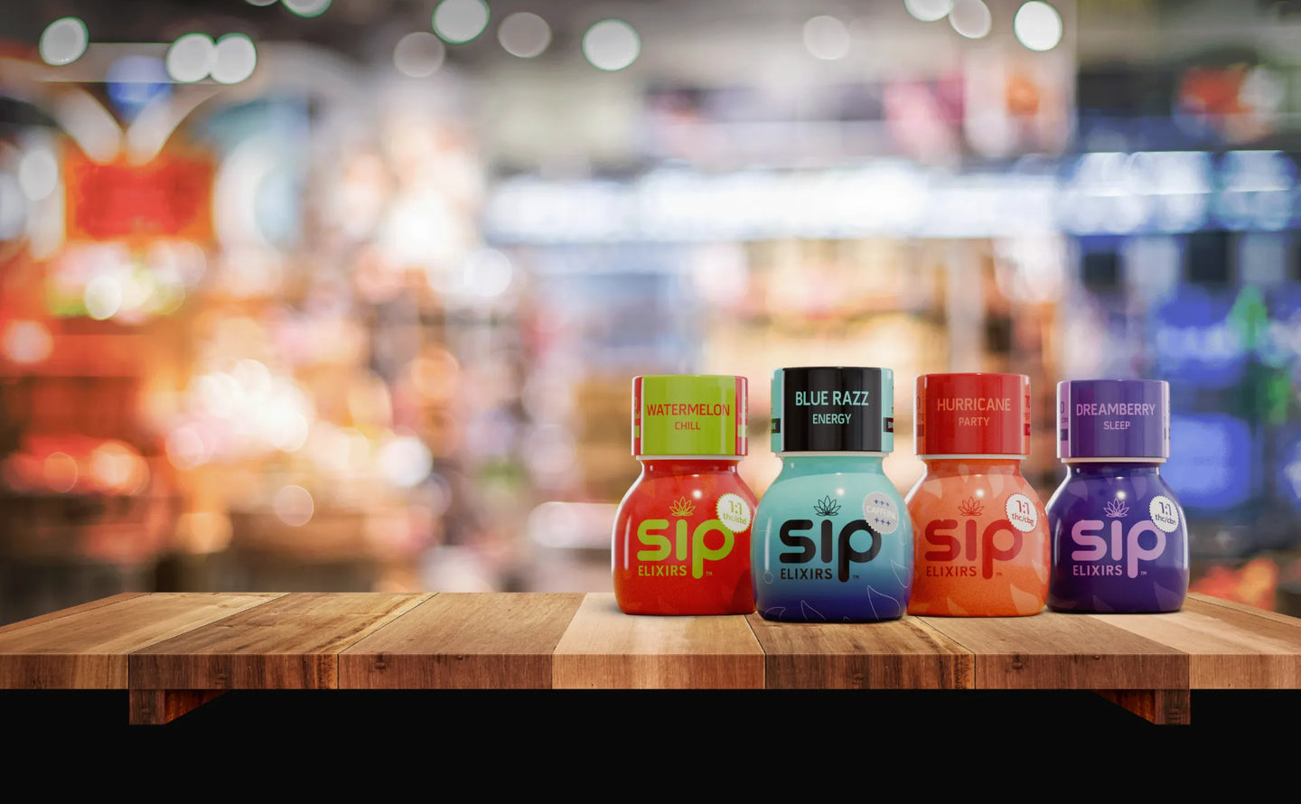 Four colorful 'sip' bottles on a wooden table with a blurred background
